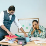 Dua orang di kantor sedang berdiskusi serius mengenai dokumen surat peringatan kerja